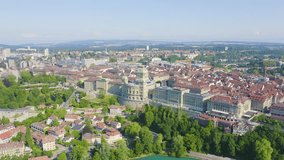 Inscription on video. Bern, Switzerland. Federal Palace - Bundeshaus, Historic city center, general view, Aare river. Arises from blue water, Aerial View