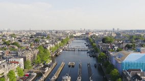 Inscription on video. Amsterdam, Netherlands. Flying over the city rooftops. Amstel River, Amstel Gateways. Text furry, Aerial View