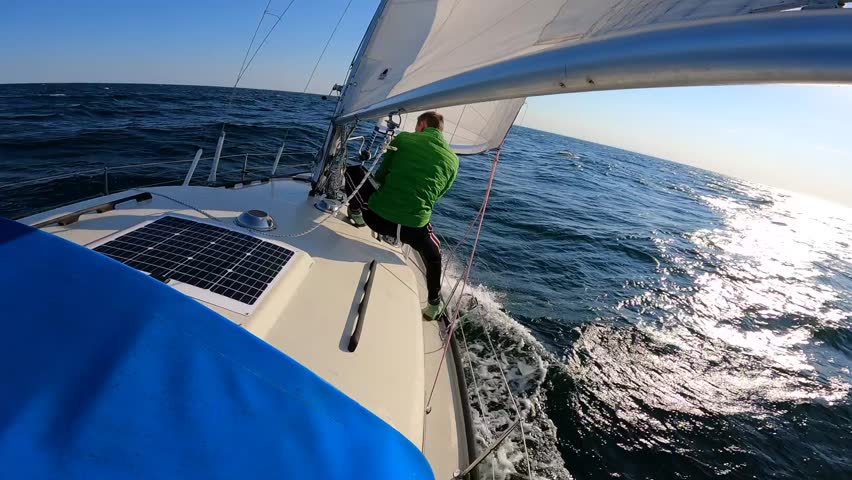 Young sailor managing sails on Sailboat in open, rough and wavy sea. adrenaline, adventure concept