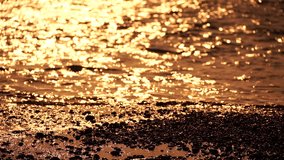 Blurred golden sea at sunset. The sun reflects and sparkles on the waves with bokeh, illuminating the golden sea. Holiday recreation concept. Abstract nautical summer ocean sunset nature background
