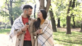 Couple in love walking on autumn park, drink coffee enjoying a beautiful autumn day