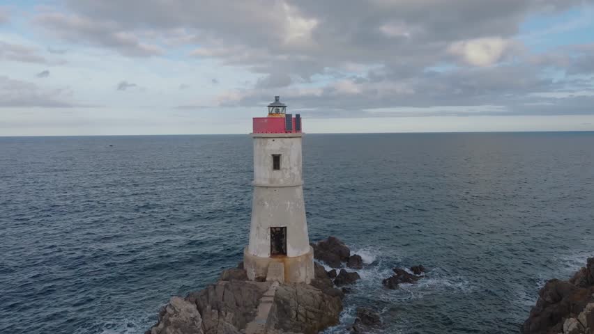 Old lighthouse on a cliff at sunset

