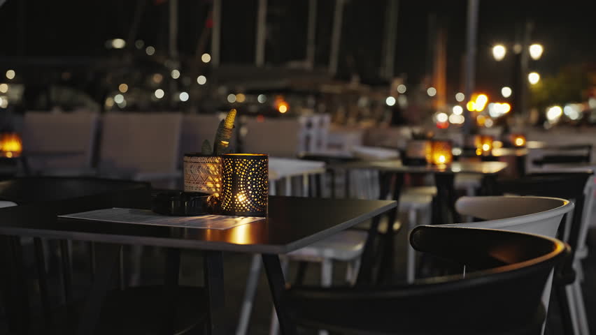Blurred of interior of large beautiful restaurant with bright lighting. Waitress comes to table, gives visitors menu and goes for drinks. Defocused interior and restaurant visitors. Lifestyle