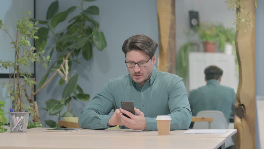 Upset Middle Aged Businessman Reacting to Loss on Smartphone