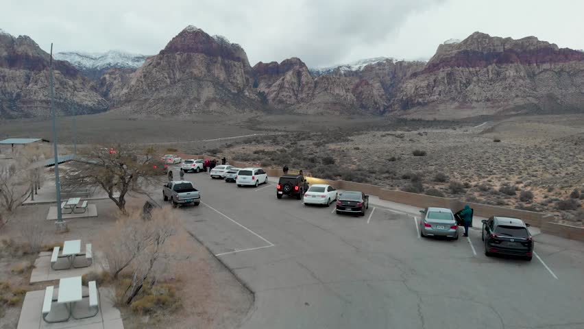 Drone 4K. Red Rock Scenic Overlook. Vehicles, people, winter sky, clouds, snow capped mountains. Las Vegas, NV. Lower flight.