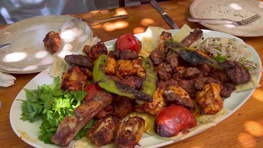 Eating a traditional Turkish big meat platter mixed grill with vegetables and fresh pide ekmek bread in Bodrum Turkey, authentic tasty food, 4K shot