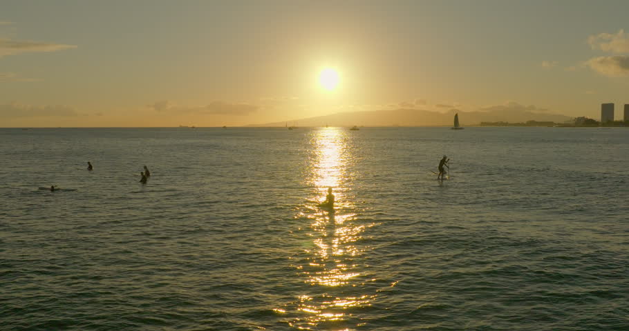 Aerial: Slow Motion Drone Shot Of People With Surfboards In Sea Against Sky During Vacation - Waikiki, Hawaii