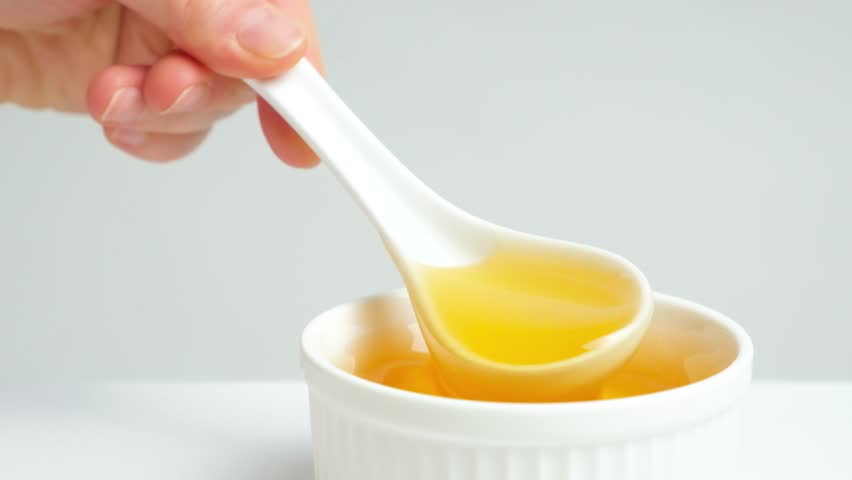Liquid bee honey in a spoon, showing linden fresh honey on a white background.
