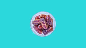 Bowl of date fruits rotating on blue background. Traditional Ramadan food for muslims. Fasting concept video.