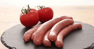  raw sausages rotate on a tray with vegetables. ready to fry. traditional cuisine. High quality 4k footage