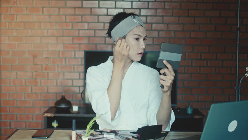 Young Asian transgender man doing makeup