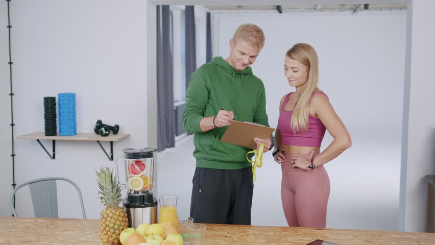 A young beautiful caucasian woman and her personal coach review the training schedule and give the high five - a healthy lifestyle concept | Shutterstock HD Video #1099319587