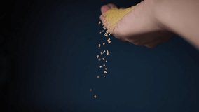Falling grains of couscous on hand and blue background. Selective soft focus. Videos.
