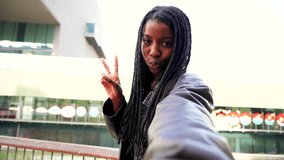 POV screen view of one african american young woman with braids smiling having a video call with a smartphone device. Front view of a happy girl taking a selfie portrait. High quality 4k footage