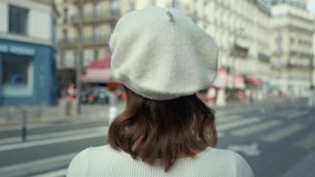 Young tourist in a white beret looking at a bistro by the road