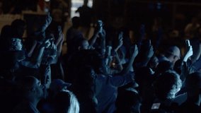 A night concert and a blue glowing stage. Crowd of fans at a concert of their favorite band. People are filming a concert on their phone. Raised hands. - Powered by Shutterstock - Get 15% off with code: PIKWIZARD15