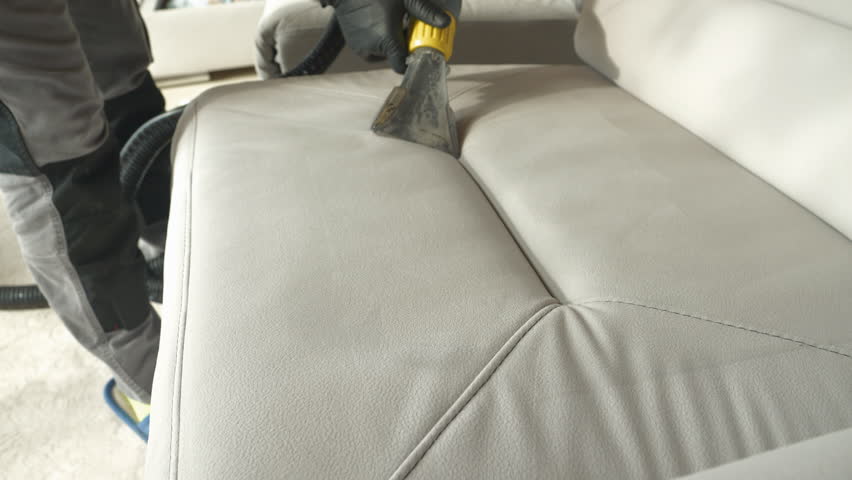 CLOSE UP: Deep cleaning white upholstered furniture surface with vacuum cleaner. Revealing clean fabric at thorough washing and vacuuming of sofa as a mandatory household chore during spring-cleaning. Royalty-Free Stock Footage #1099322505