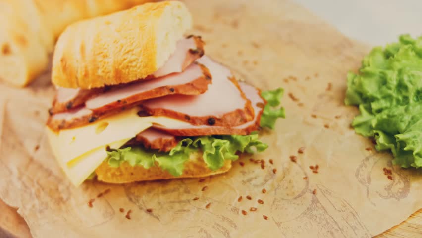 Waviness effect of Sandwich with French baguette, cheese, lettuce and sausage. Slider shooting. In the background is a retro baking tray and cooking paper | Shutterstock HD Video #1099322957