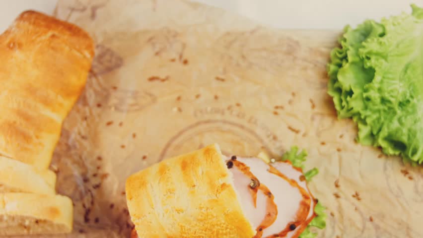 Waviness effect of Sandwich with French baguette, cheese, lettuce and sausage. Slider shooting. In the background is a retro baking tray and cooking paper | Shutterstock HD Video #1099322967