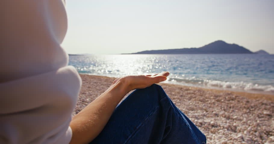 Female hand making zen stone tower on sea beach. Close up shot