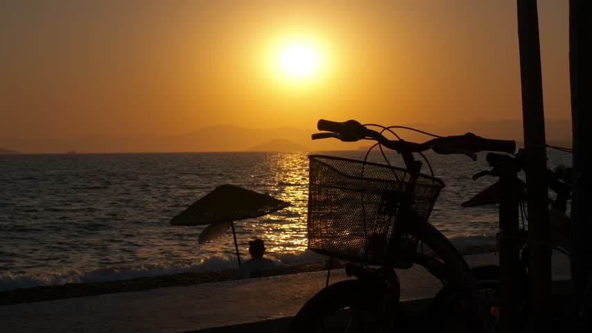 Bicycle at sunset on the sea beach. A view of bicycle silhouette stoped on the evening tropical sandy beach during summer period.