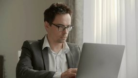 Busy freelancer works remotely from home office. Serious businessman in glasses doing an online research. High quality 4k footage