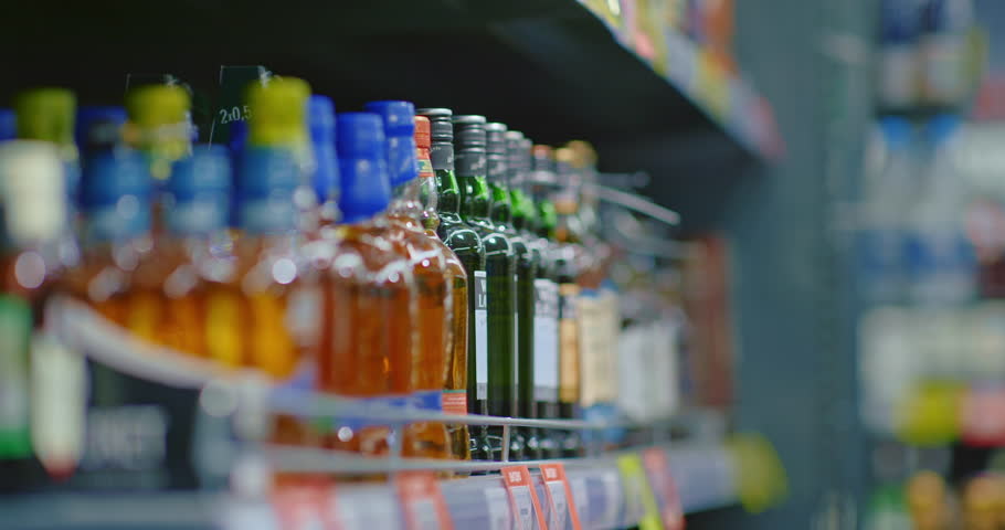 man choosing whiskey in store, taking bottle from shelf, closeup view of hand, 4K, Prores