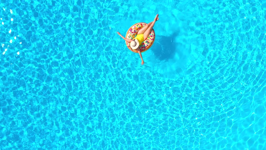 Top down view of a woman in yellow swimsuit lying on a donut in the pool Royalty-Free Stock Footage #1099334561