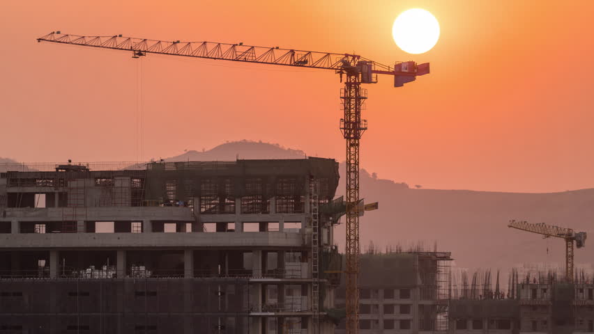 A beautiful time lapse of sun setting behind the mountains and an under construction building in an Indian metro city, India