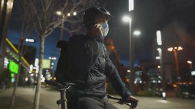 Male delivery man with bicycle wearing helmet and protective mask from covid virus and pollution, delivers parcels in city at night on bike, making phone call to client during coronavirus quarantine. - Powered by Shutterstock - Get 15% off with code: PIKWIZARD15