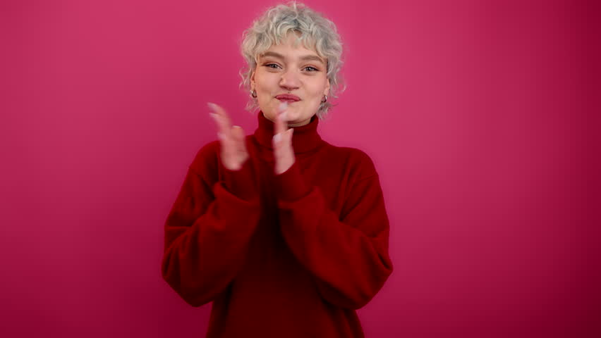 Close-up view of young adult looking at camera. Portrait of caucasian, blonde-haired woman enjoying red, heart-shaped balloons. High quality 4k footage