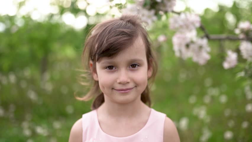 Portrait of little girl wearing light pink dress among blooming apple trees. Living in harmony with nature concept | Shutterstock HD Video #1099341379