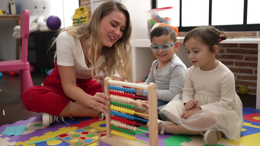 Teacher with boy and girl learning maths with abacus sitting on floor at kindergarten Royalty-Free Stock Footage #1099347643