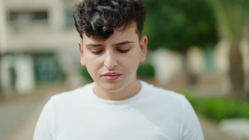 Non binary man standing with serious expression at park