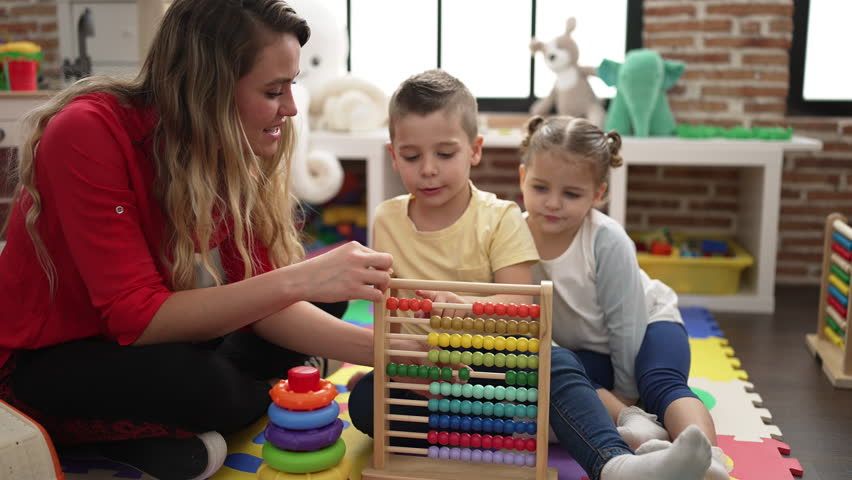 Teacher with boy and girl learning maths with abacus sitting on floor at kindergarten Royalty-Free Stock Footage #1099348791
