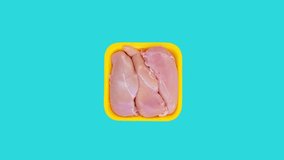 Raw chicken meat rotating on blue background. Top view footage of uncooked chicken meat.