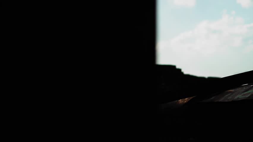 The silhouette of a guy who sits down to rest on metal structures in the industrial zone.