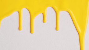 Liquid drops of yellow paint color flowing on the white surface. Macro Shot of yellow paint dripping on the white wall with copy space. Production Close-up. Slow Motion, Abstract art.  - Powered by Shutterstock - Get 15% off with code: PIKWIZARD15