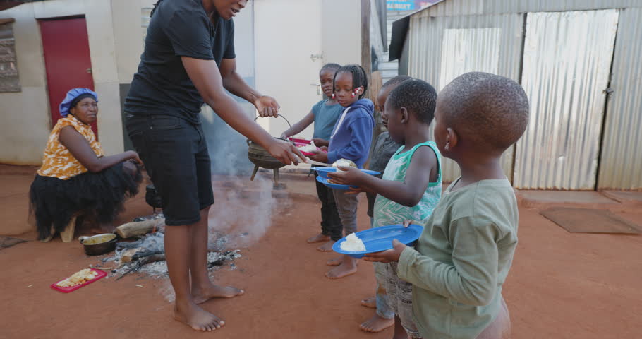 Poverty in Africa. Hungry African children holding out plates while a charity organisation distributes food Royalty-Free Stock Footage #1099354519