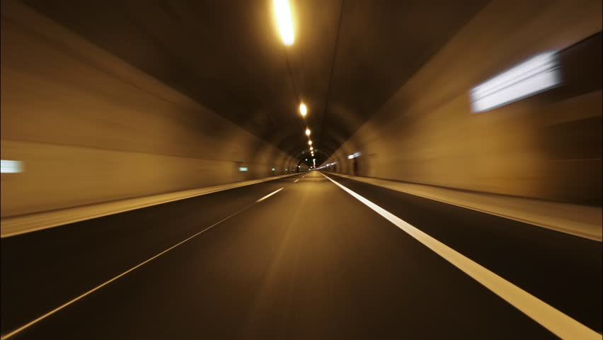 Transition Highway car tunnel illuminated with bright orange lights front view from moving car loop along median in mountains on family trip in summer. Ending transition in tunnel to white Royalty-Free Stock Footage #1099354587