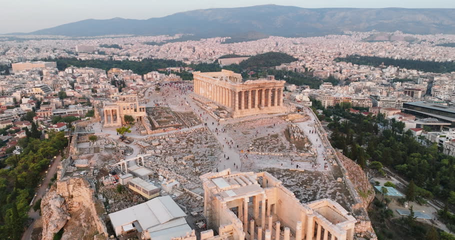 Greece Acropolis city of Athens parthenon symbol ancient aerial view hill slide from drone on panorama of residential buildings at sunset summer. Lights sun, lens flare. World Heritage sites. History