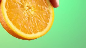 Squeezing juice from half an orange close-up. crush of citrus. fresh fruit on a green background. High quality 4k footage