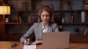 Adult business woman wearing headphones communicating by video call or speaking looking at laptop computer, online conference distance office chat, virtual training concept.