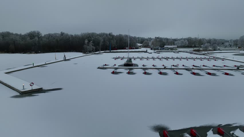 Aerial View of dead frozen harbour docks with lonely boat and ice. Extreme cold weather. Nature landscape famous for being heavily affected by global warming and Climate Change. Mooring for yachts
