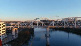 Nashville Tennessee USA - 1 16 2023: aerial footage of the John Seigenthaler Pedestrian Bridge with people walking along the bridge surrounded by the Cumberland River, winter trees and blue sky