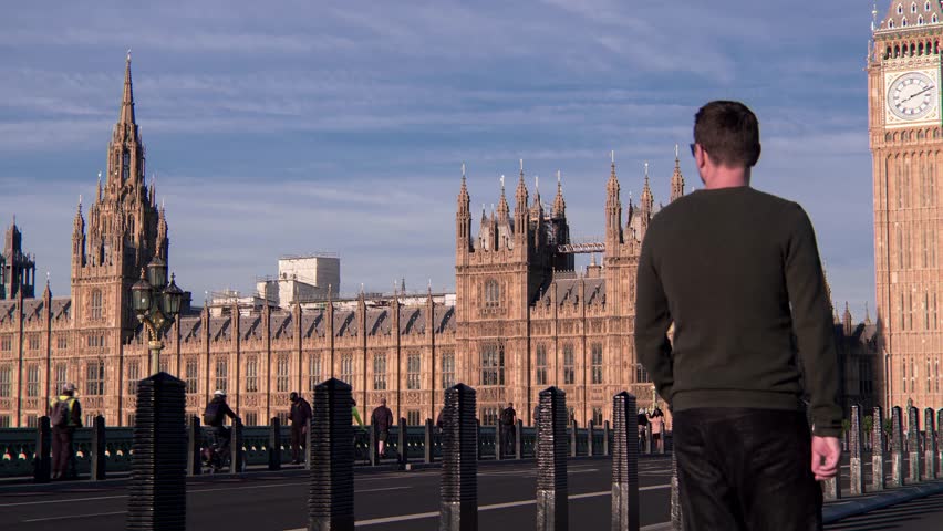 Attractive European looking man walking on Westminster Bridge London on a morning crowded sunny day, with Palace of Westminster Big Ben view, London England Royalty-Free Stock Footage #1099367119