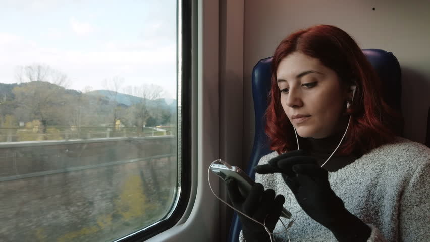 Girl with earphones listening music while travel by train