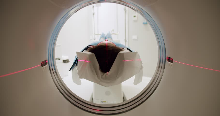 Woman during CT scanning procedure. Tracking shot of female patient lying on table sliding into CT machine near crop doctor in laboratory of modern clinic.Modern technologies.Shot Of CT Scanning Room. | Shutterstock HD Video #1099371681