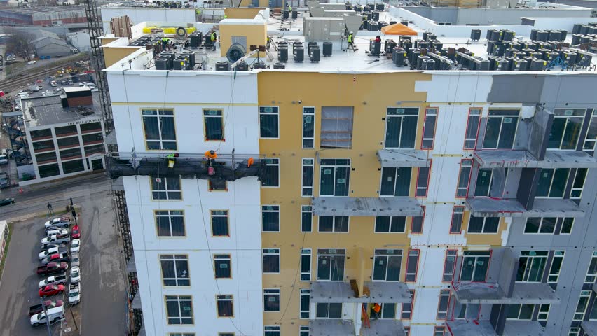 tilt aerial footage of a hotel under construction with construction workers working on the side of the building in Nashville Tennessee USA
