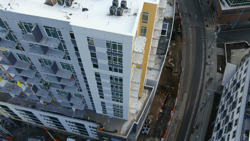 sideways aerial footage of a hotel under construction with construction workers working on the side of the building in Nashville Tennessee USA